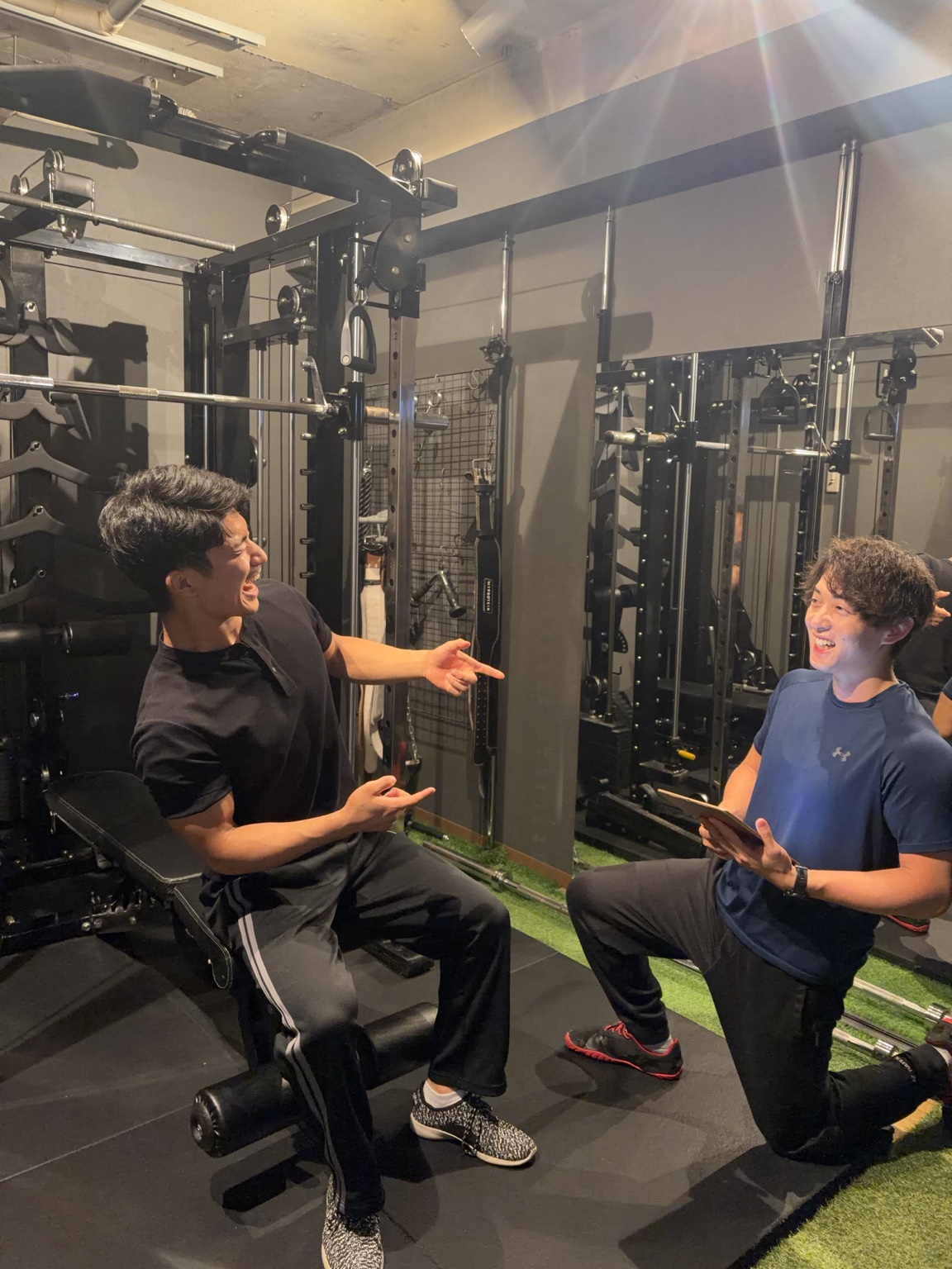 ジムで笑顔で話すLAST PERSONAL GYMのトレーナー2名